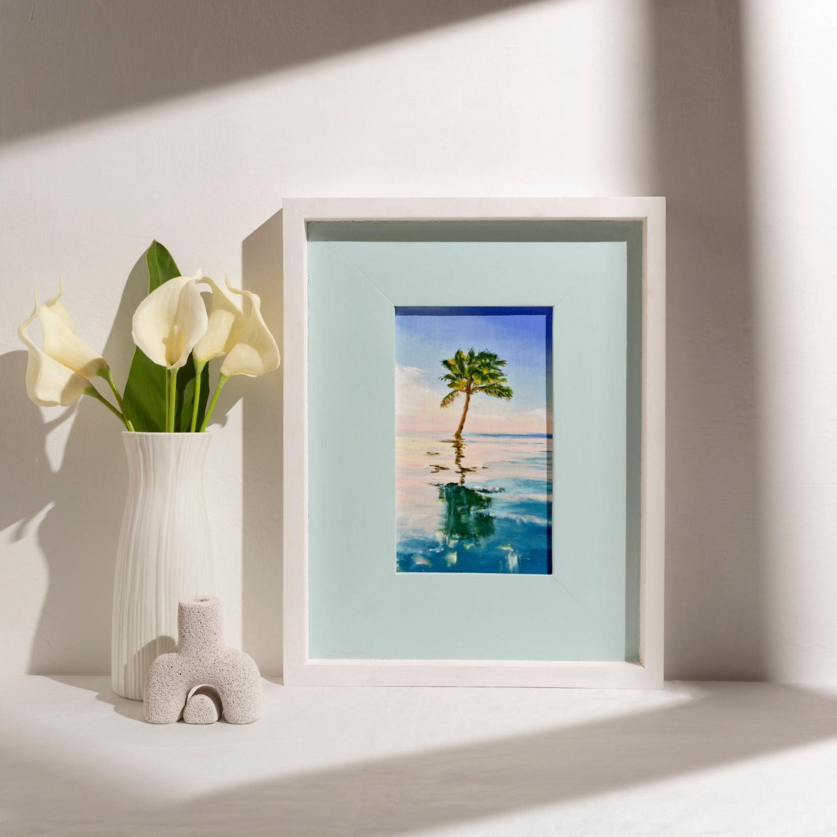 Lone Palm, palm tree art print in white frame on table with flowers and ornaments