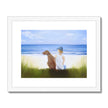 Boy and dog sitting overlooking the beach. Painting. Art print in white frame with white mount