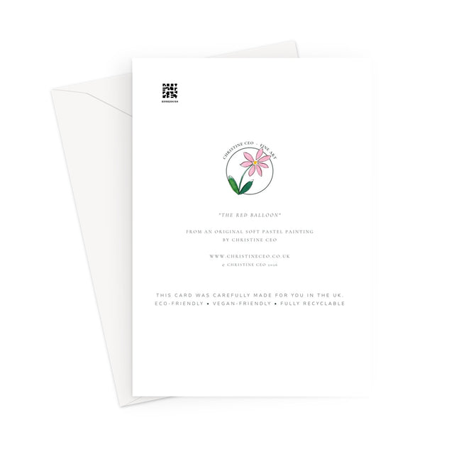 Greeting card back view. A white card with printed text and a small floral illustration, shown with a white envelope behind it on a light gray background.