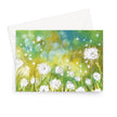 Greeting card with a delicate painting of white fluffy dandelion seed heads on a bokeh background