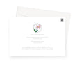 Greeting card back. A white greeting card with a soft pink flower and green leaves, shown with a white envelope behind it on a light gray background.