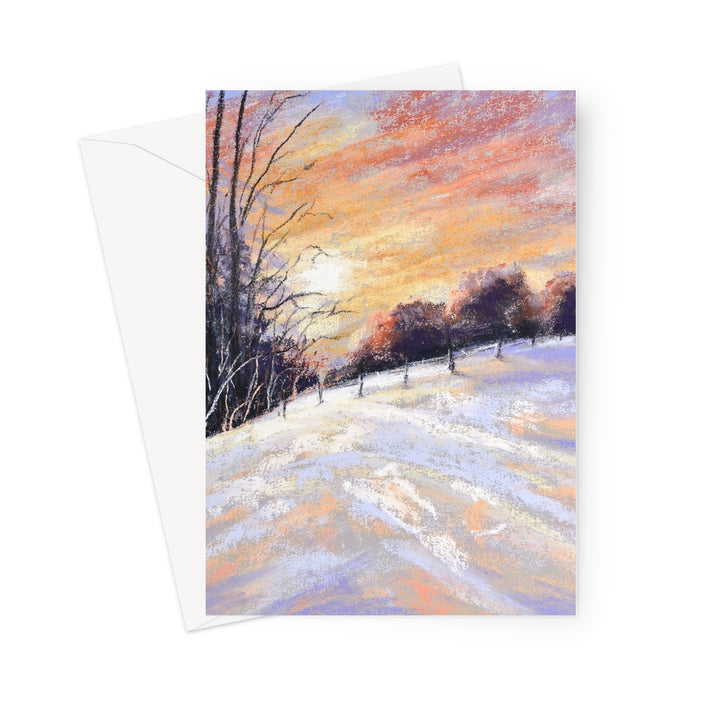 A vertical greeting card featuring a pastel landscape painting of a snowy field at sunset, shown with a white envelope behind it.
