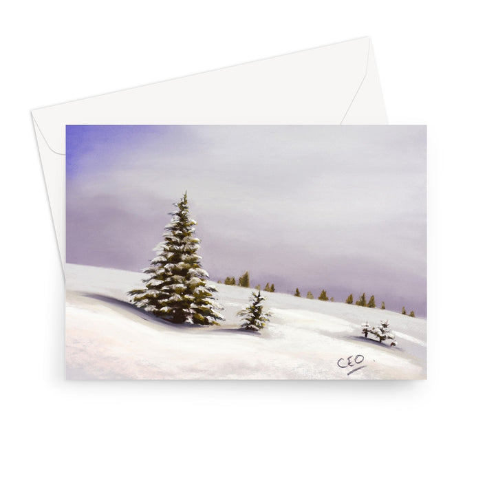 A landscape format greeting card featuring a painted winter landscape with snow-covered ground, evergreen trees, and a soft lavender sky, shown with a white envelope behind it on a light gray background.