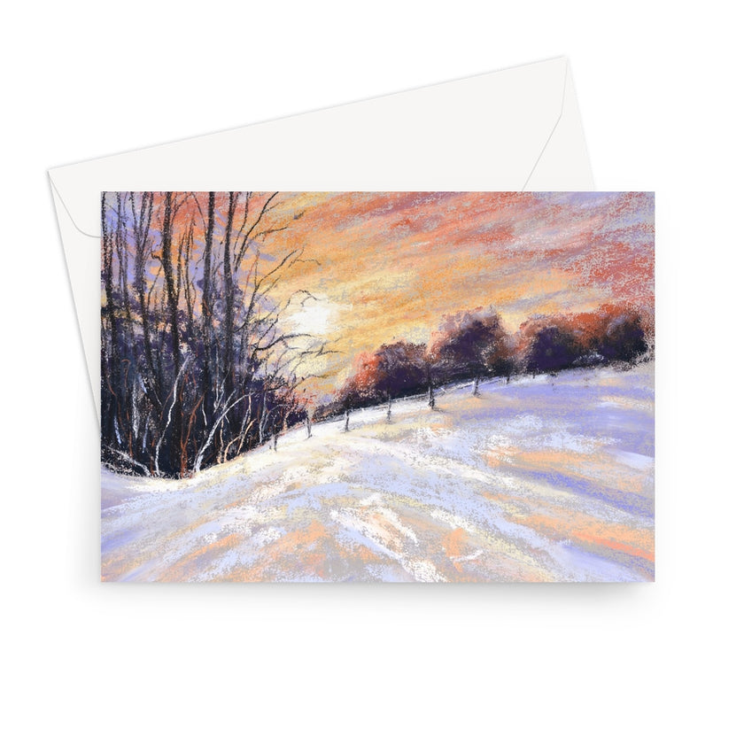 A landscape format card featuring a snowy landscape with bare trees and a warm orange sky, shown with a white envelope behind it on a light gray background.