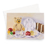 A greeting card featuring a teddy bear, a white rabbit, and colorful ornaments, shown with a white envelope.
