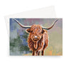 A rectangular art print or card featuring a painted Highland cow with long curved horns, shown in front of a white envelope on a light gray background.