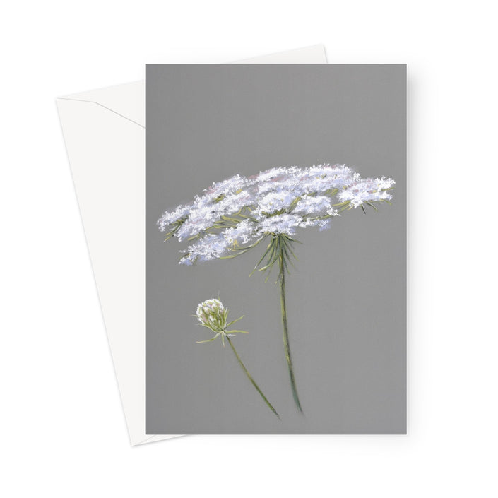 A vertical art print or card featuring a botanical illustration of white wildflowers on a gray background, shown with a white envelope behind it on a white studio background.