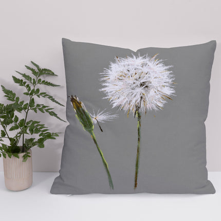 A square throw cushion with a gray background featuring a handcrafted white dandelion seed head design