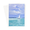 A vertical art print or greeting card featuring a painted seascape with a small white sailboat on turquoise water under a blue sky, shown with a white envelope behind it on a light gray background.