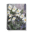 Notebook with a floral design on the cover featuring white flowers on a colourful background