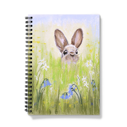 Notebook with a rabbit illustration on the cover, featuring a rabbit peeking from grass and flowers.