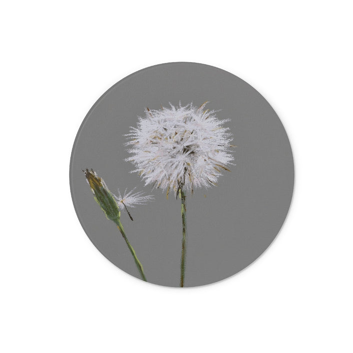 Circular chopping board, Dandelion seed head on a grey background