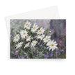 A landscape format greeting card featuring an impressionistic painting of white daisies with yellow centers among green and purple foliage, shown with a white envelope behind it on a light gray background.