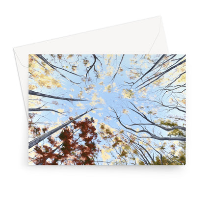 A landscape format greeting card featuring an upward-looking view of tree branches reaching toward a blue sky, with yellow and brown autumn leaves, shown with a white envelope behind it on a white background.