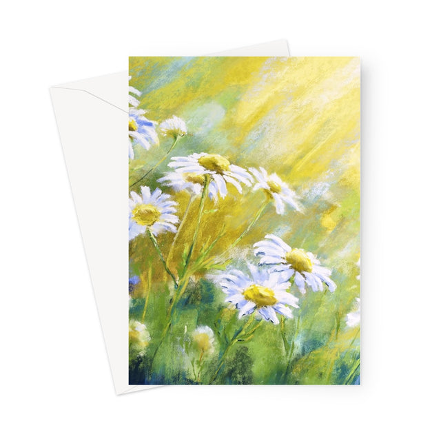 A vertical art print or greeting card featuring an impressionistic painting of white daisies with yellow centers in a sunlit green and yellow field, shown with a white envelope behind it on a light gray background.