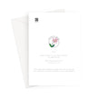 Greeting card, back view. A white greeting card with a small pink flower illustration and printed text, shown with a white envelope behind it on a light gray background.