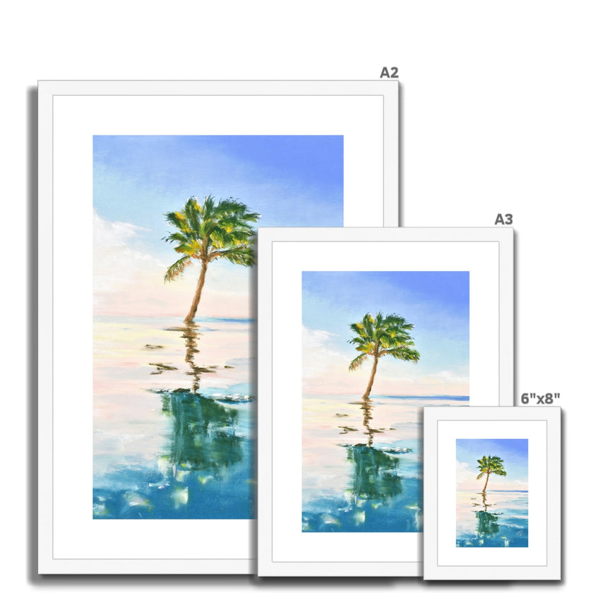 Palm tree set against blue sky and reflecting in clear turquoise water. Fine art print in a white frame with a white mount. Different sizes, smallest at the front.